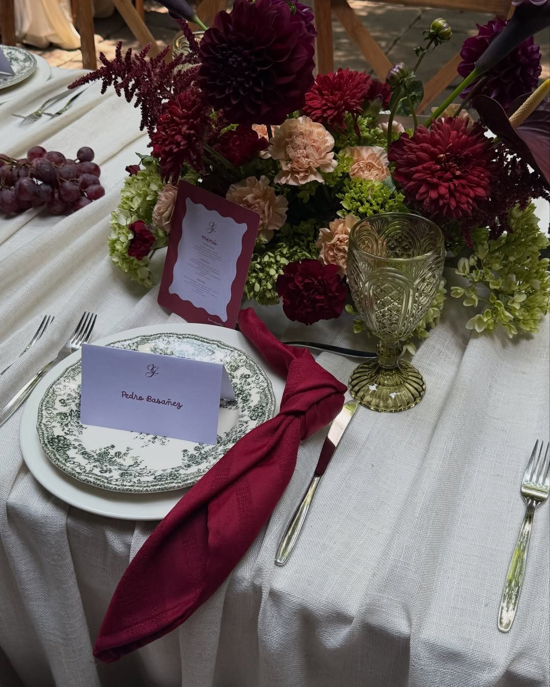 Wedding table setting with burgundy napkins and a burgundy and pink floral centerpiece.