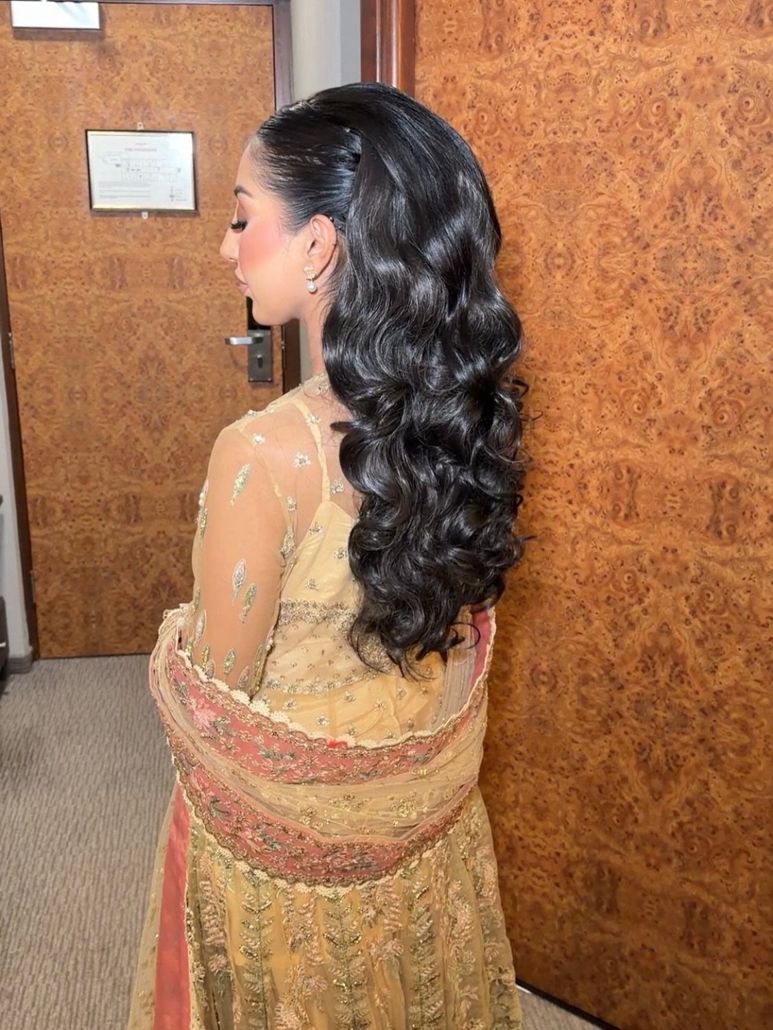 Woman with long dark curly hair and gold traditional dress in profile view