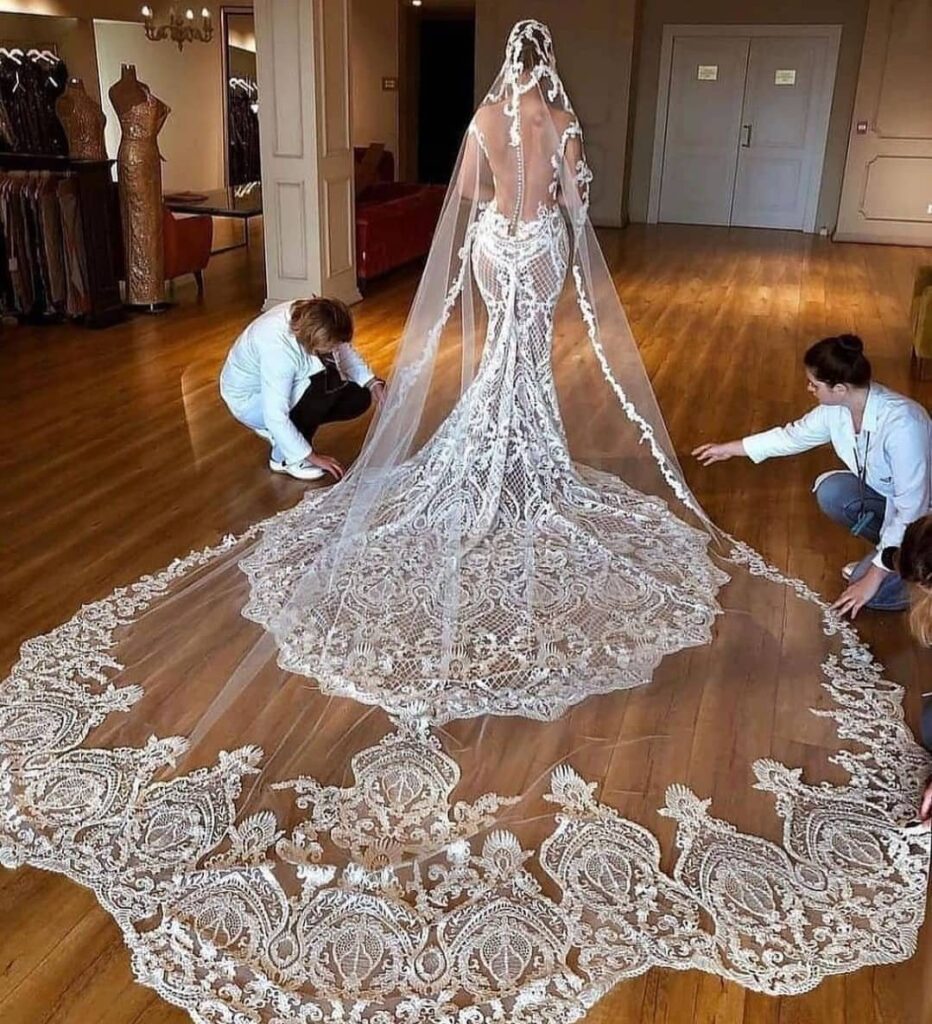 Woman in a fitted lace mermaid wedding dress with a long ornate train.