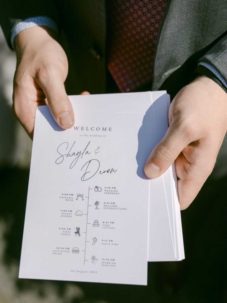 Wedding program held by a man in a suit showing a timed event schedule.