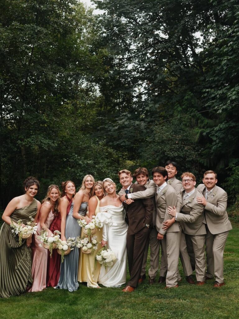 Wedding party with an uneven number of bridesmaids and groomsmen posing outdoors.