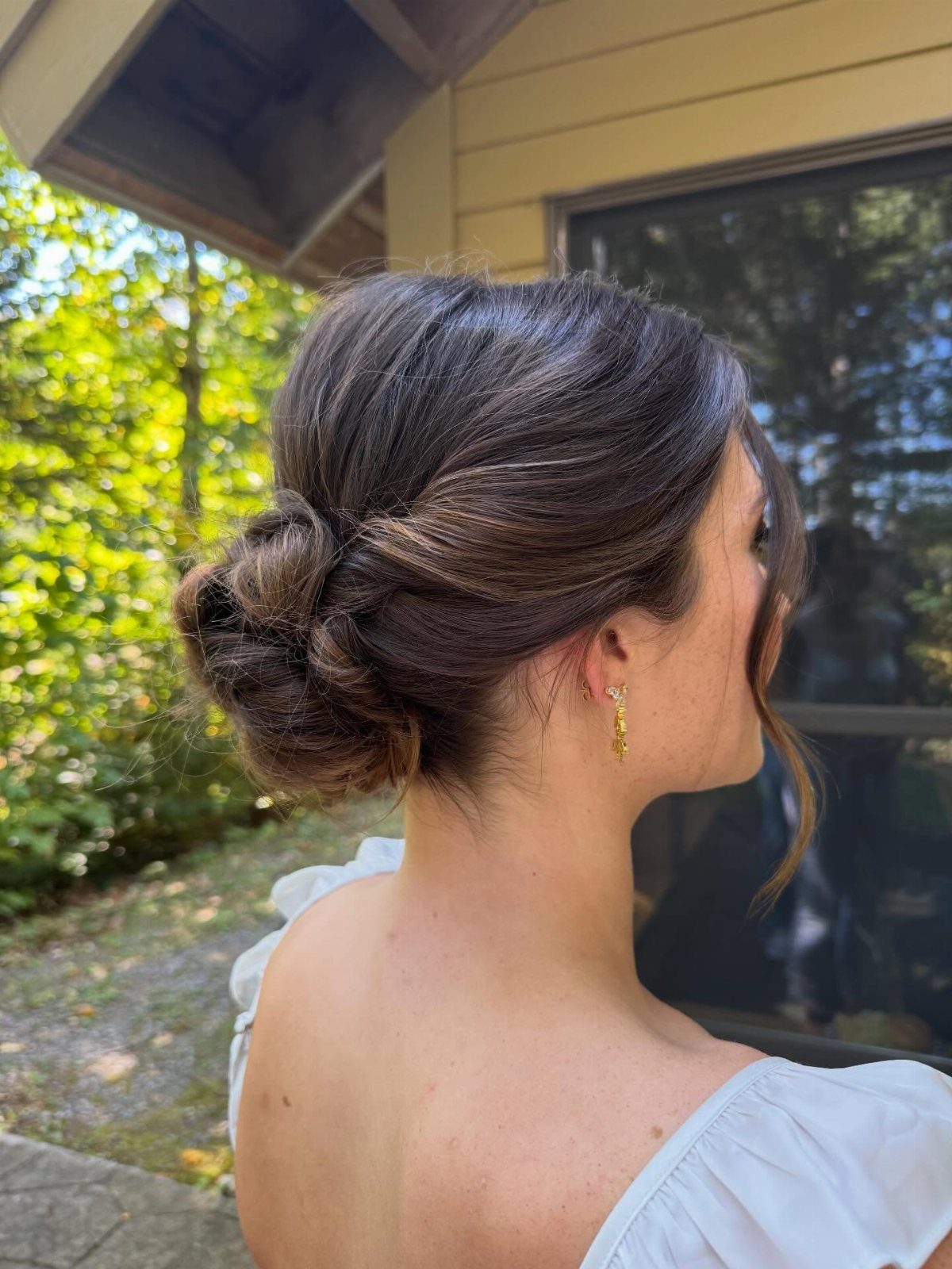 Woman with a low twisted updo bun and white off-the-shoulder top.