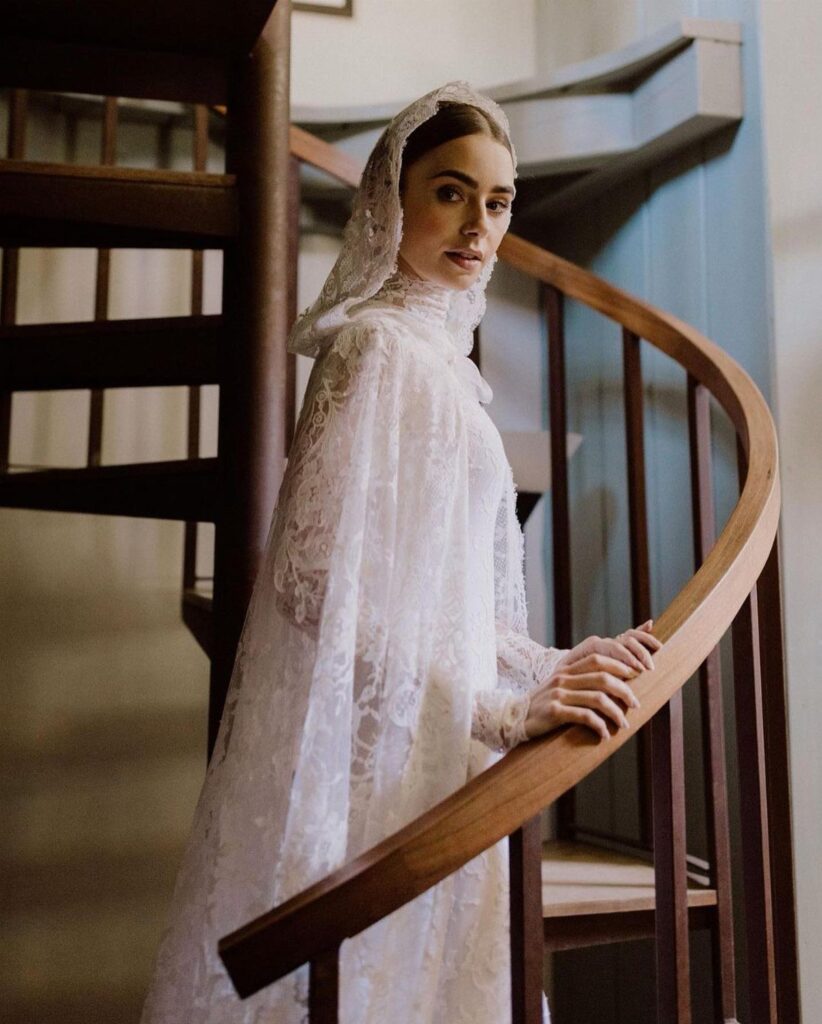 Woman in a white lace wedding dress and veil on a wooden staircase