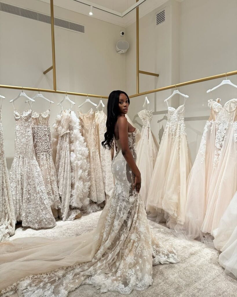 Woman in a lace wedding dress standing in a luxury bridal boutique gallery.