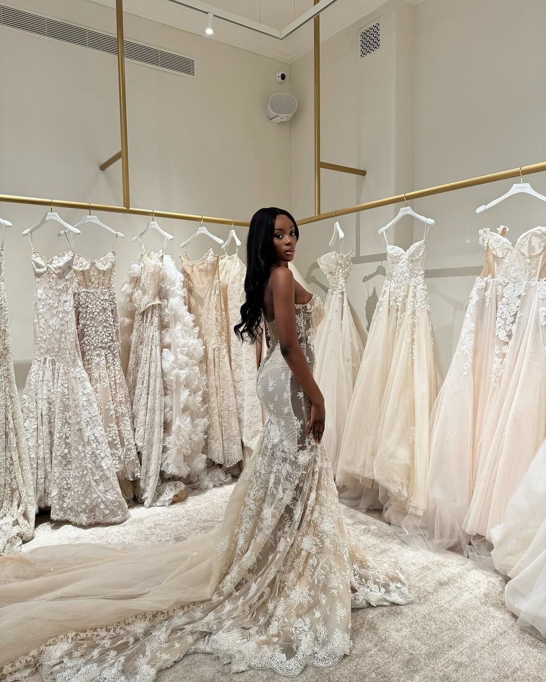 Woman in a lace wedding dress standing in a luxury bridal boutique gallery.