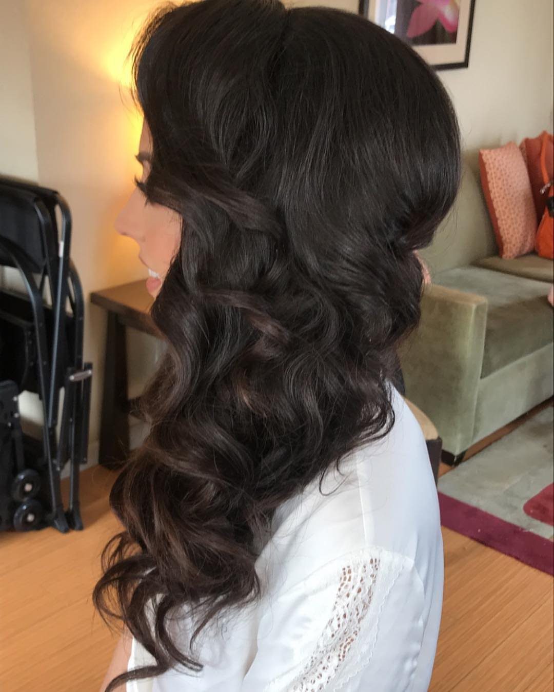 Woman with dark brown hair styled in voluminous side-swept waves over one shoulder.