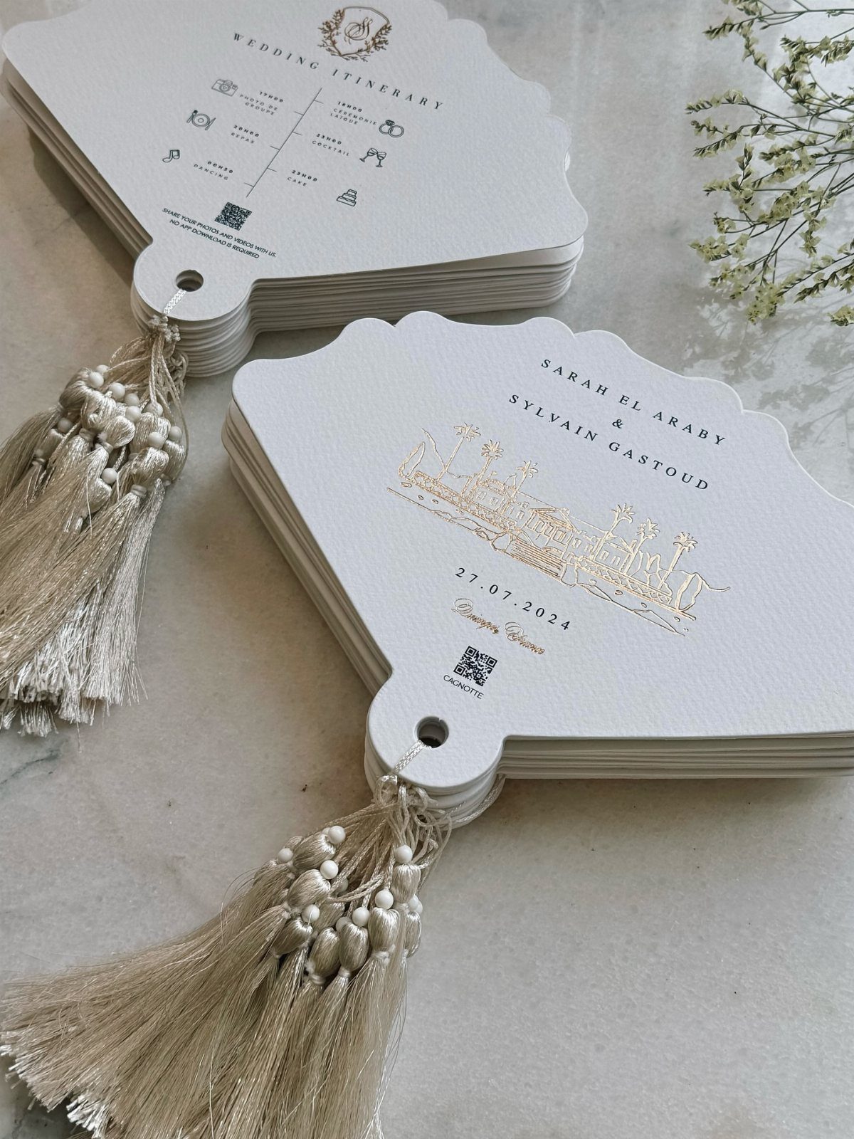 White scalloped wedding fans with gold foil lettering and elegant gold tassels.