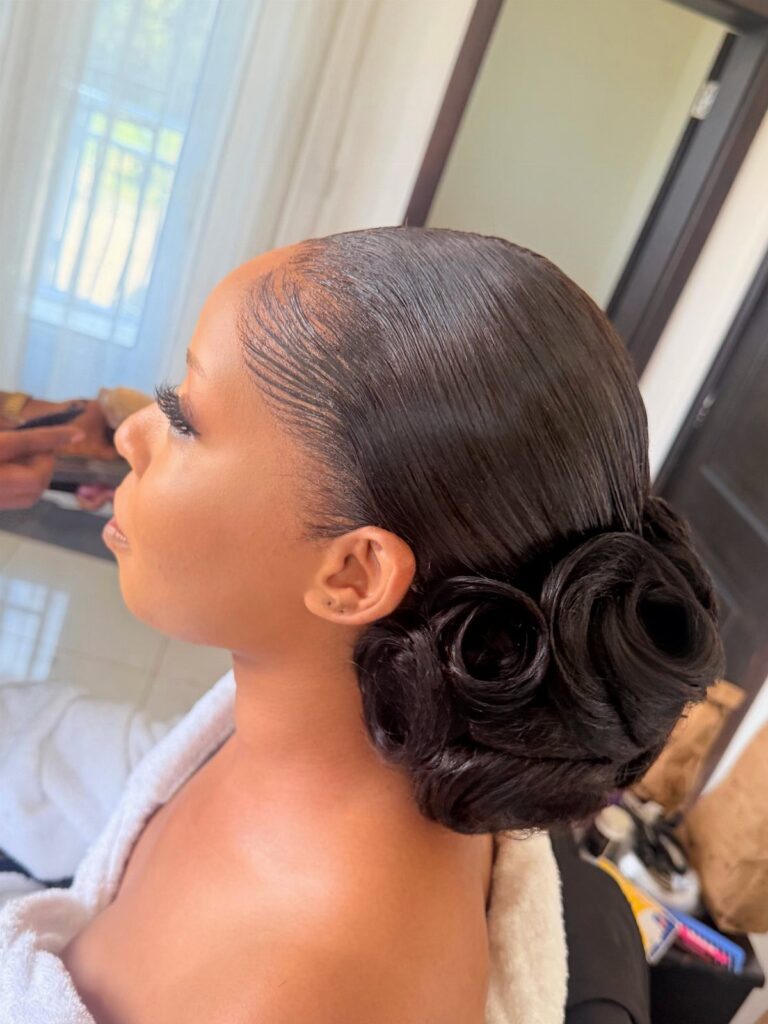 Woman with sleek straight black hair styled into a low rose-shaped bun.