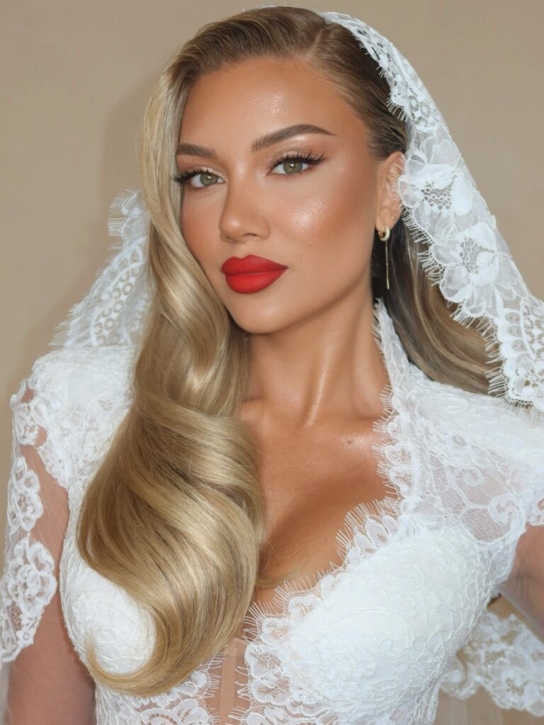 Woman in wedding veil with bold red lip color and glowing makeup