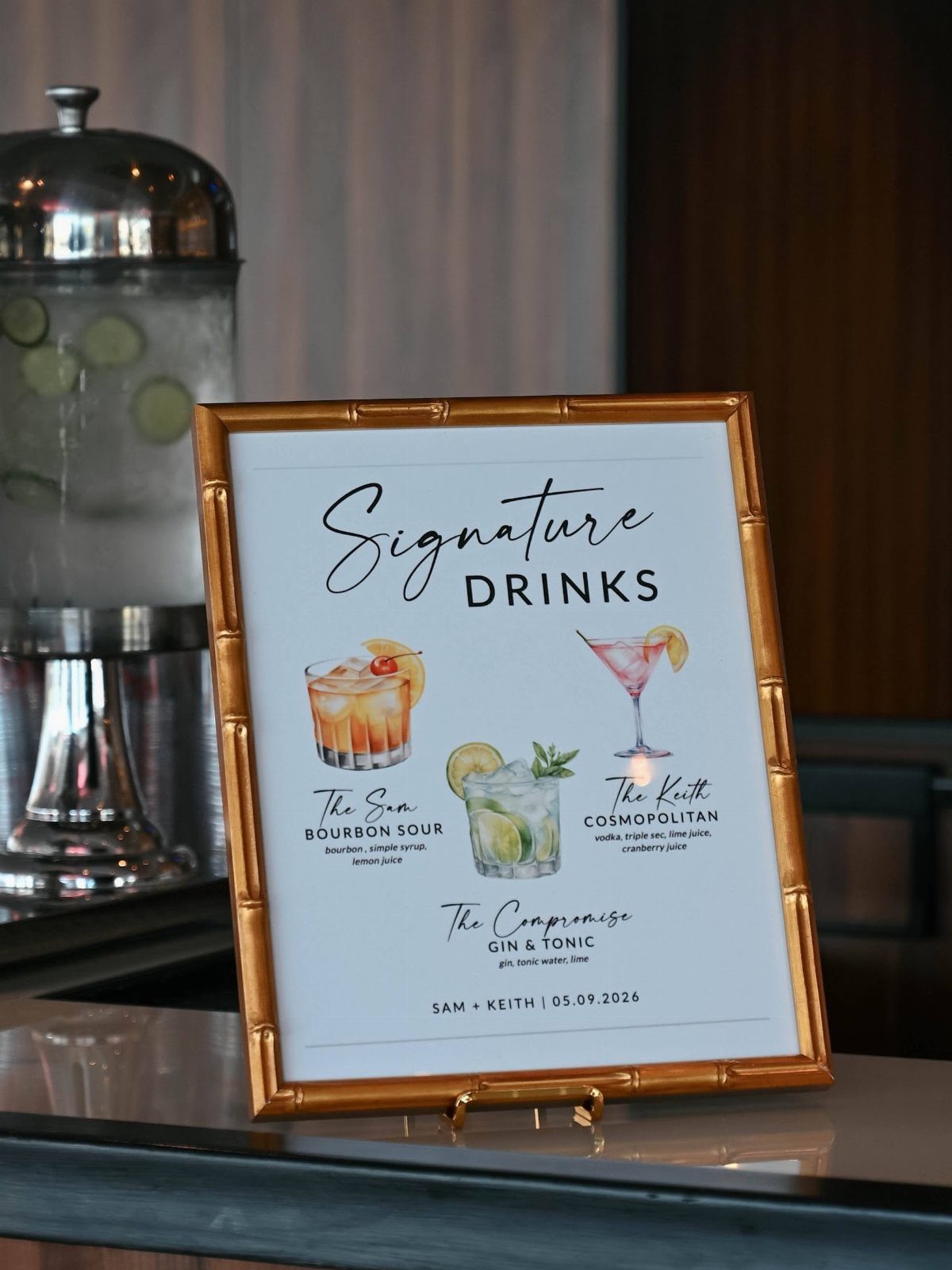 Gold framed signature drinks menu with cocktail illustrations on a bar counter